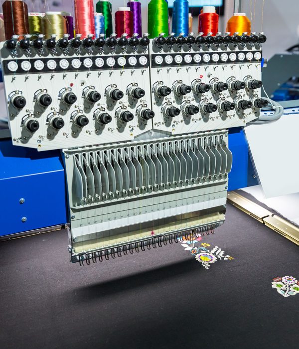Professional sewing machine embroidery color pattern on textile fabric, nobody. Factory production, sew manufacturing, needlework technology